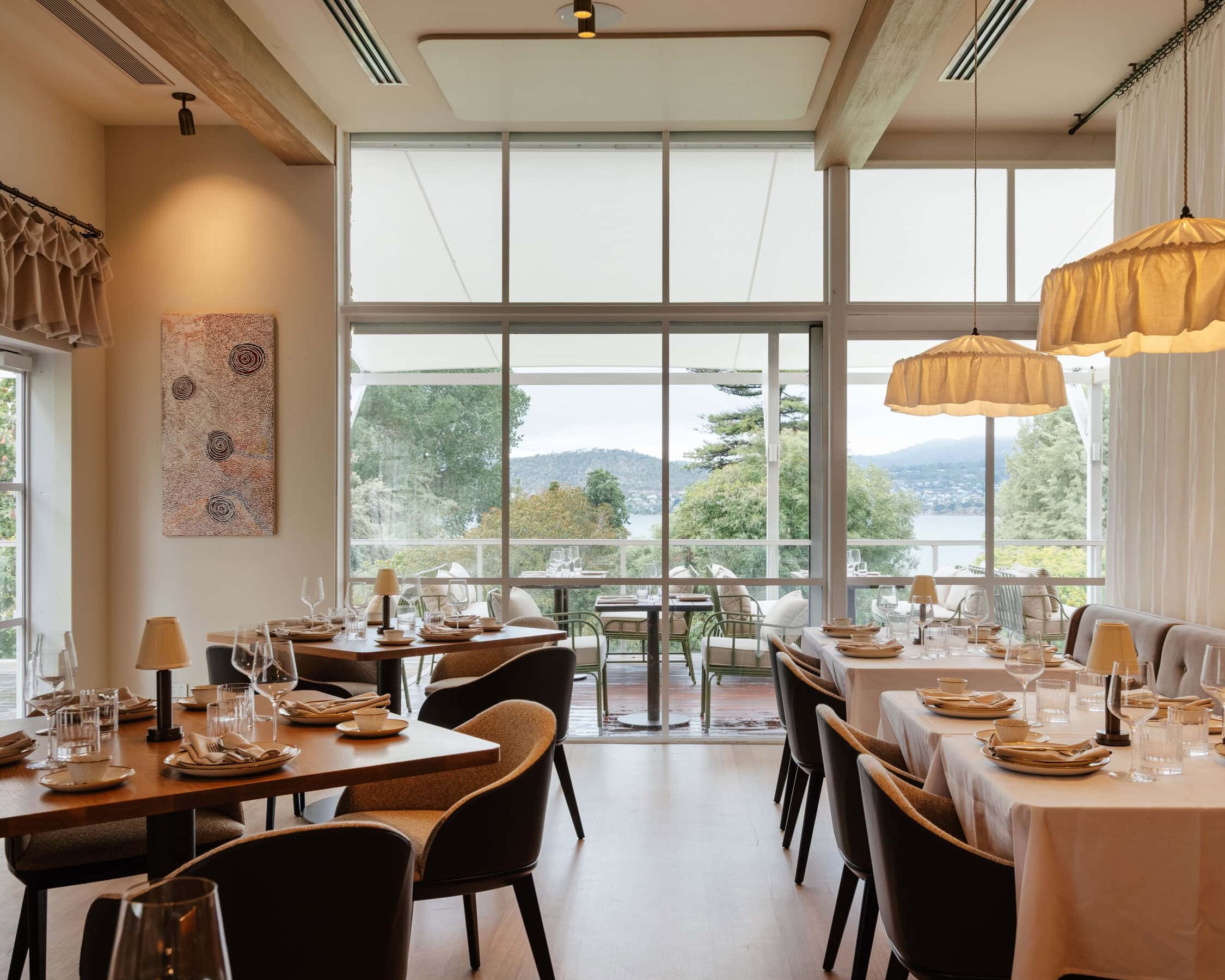 Modern restaurant interior with tables, chairs, and large windows.