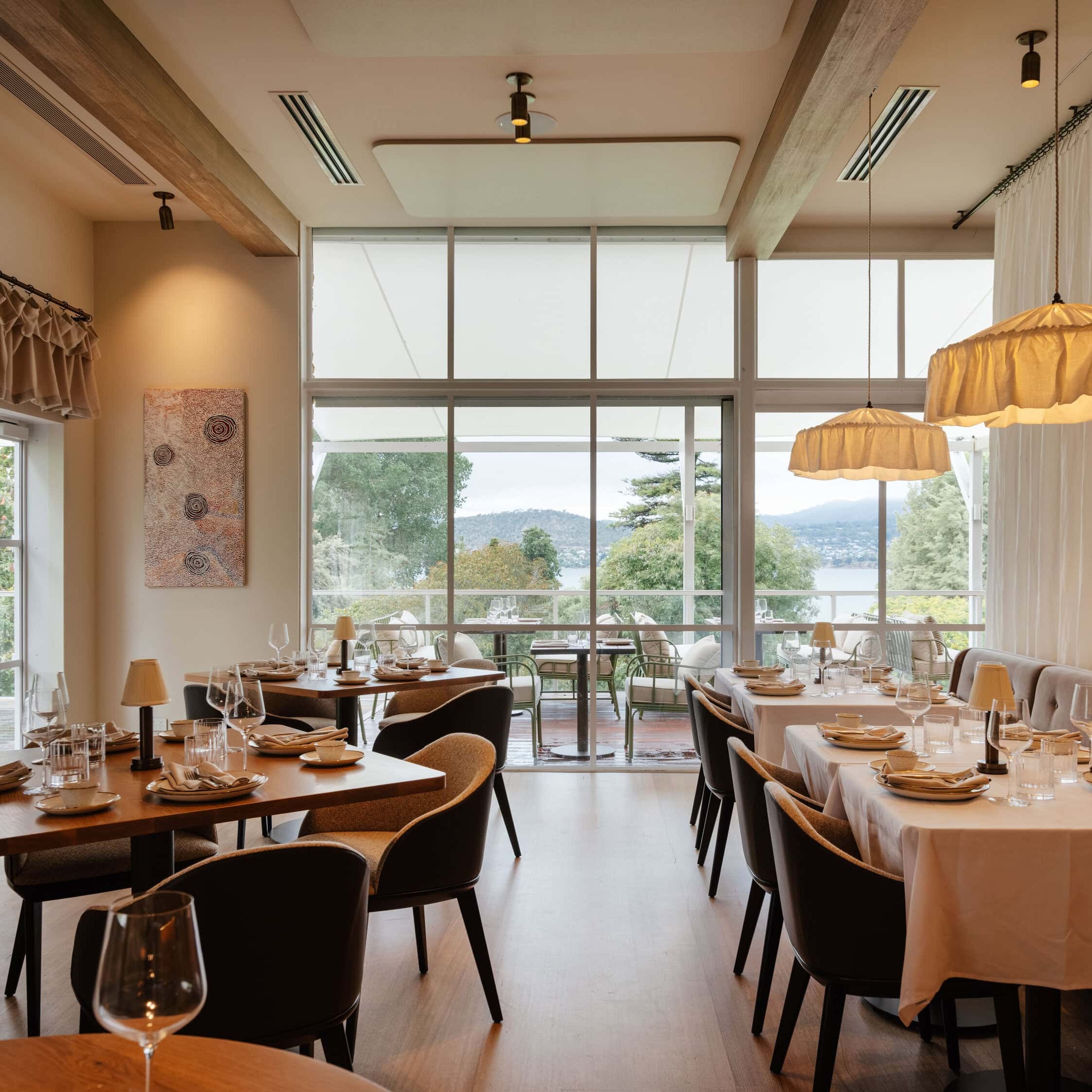 Modern restaurant interior with tables, chairs, and large windows.